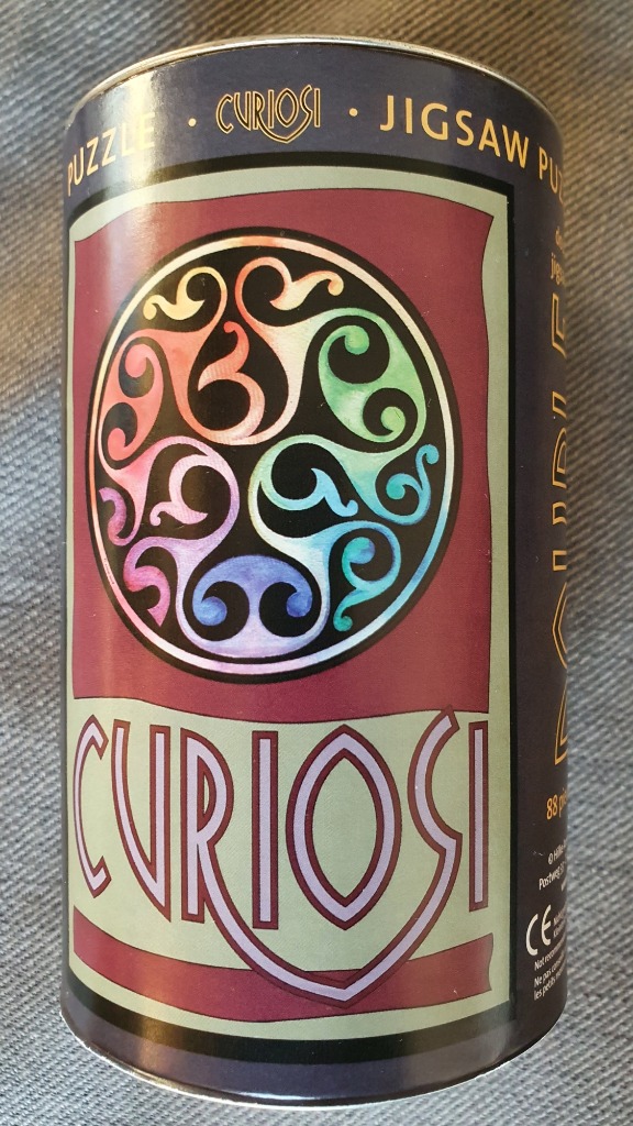 A cylindrical container featuring an art nouveau-style circular design with swirling patterns in rainbow colors.