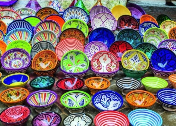 An expansive collection of colorful, patterned ceramic bowls displayed on a stone surface.