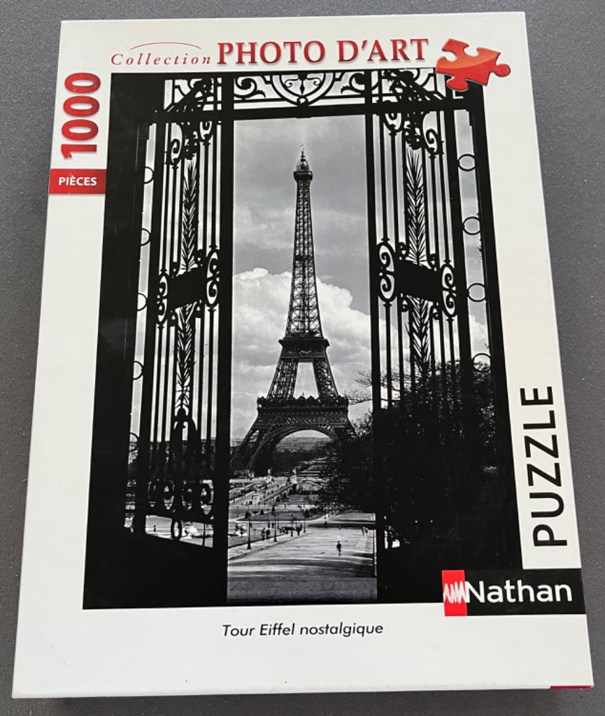 Black and white photograph of the Eiffel Tower framed by ornate wrought-iron gates.