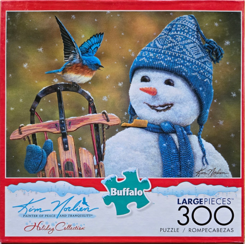 A bluebird perched on a wooden sled next to a smiling snowman wearing a blue knit hat and scarf.