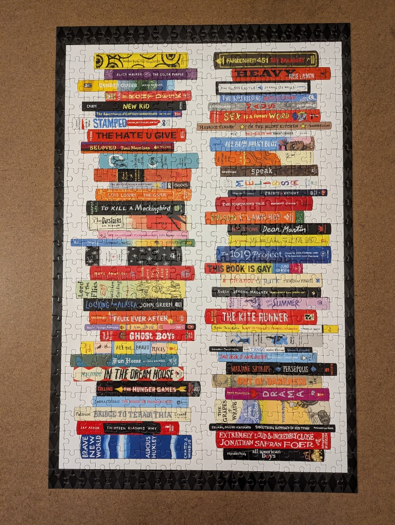 A collection of stacked book spines representing various challenged or banned books.
