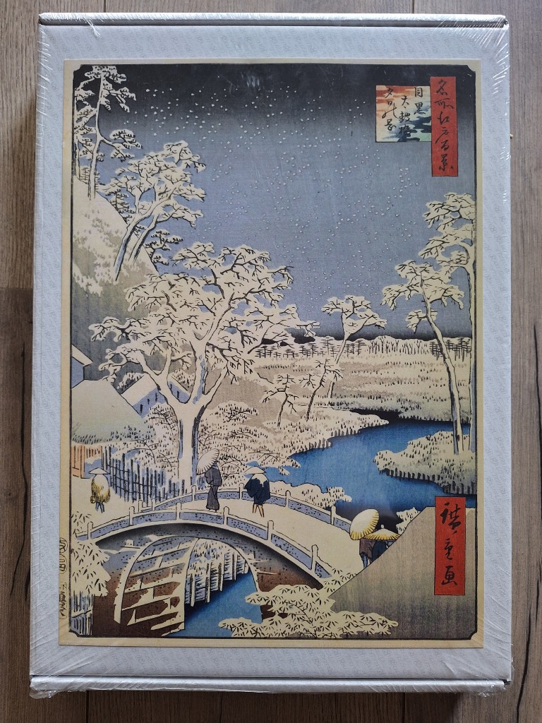 A traditional Japanese woodblock print showing figures crossing an arched bridge over a stream in a snowy winter landscape.