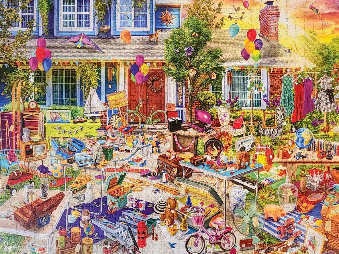 A sprawling front-yard garage sale in front of a blue and brick house with colorful decorations.