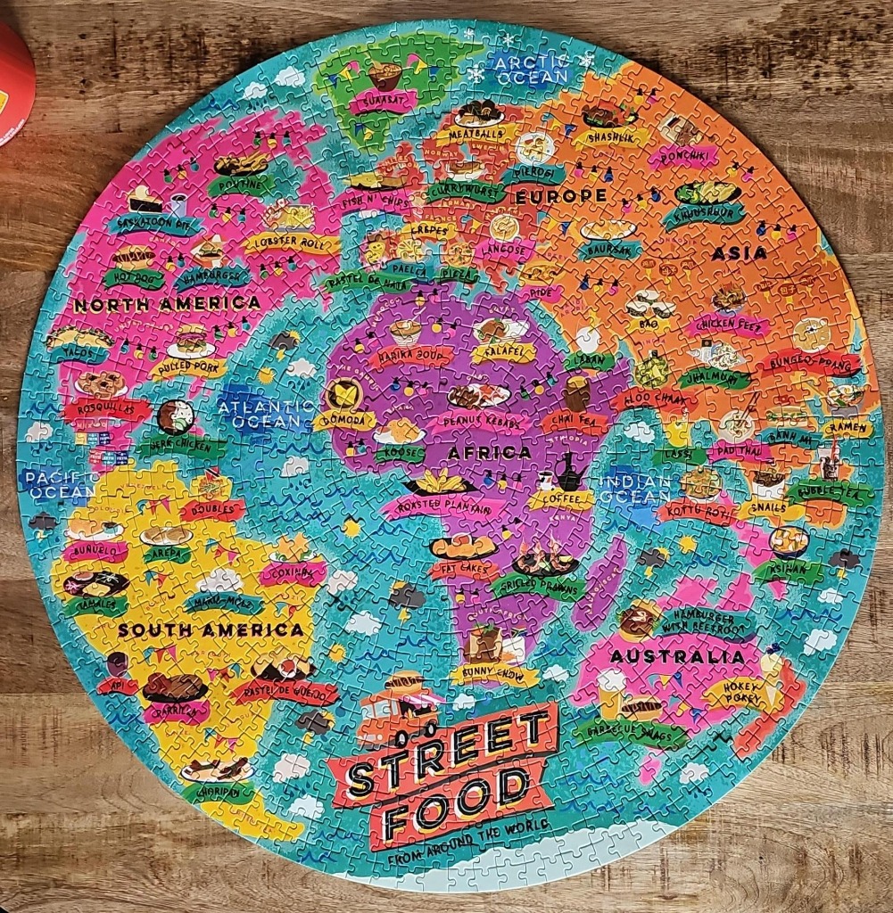 A circular world map illustration featuring popular street foods from various countries and continents.