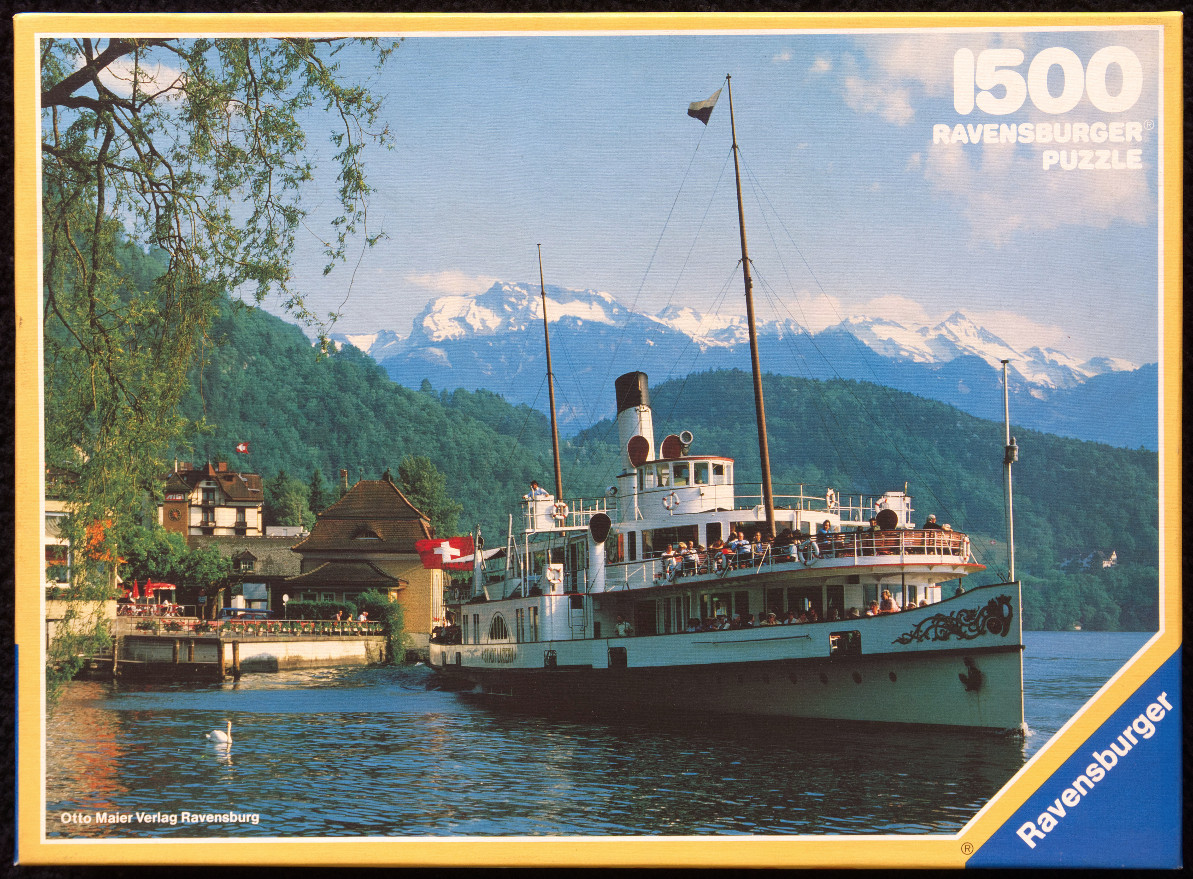 A vintage paddle steamer boat cruising on a Swiss lake with snow-capped mountains in the background.