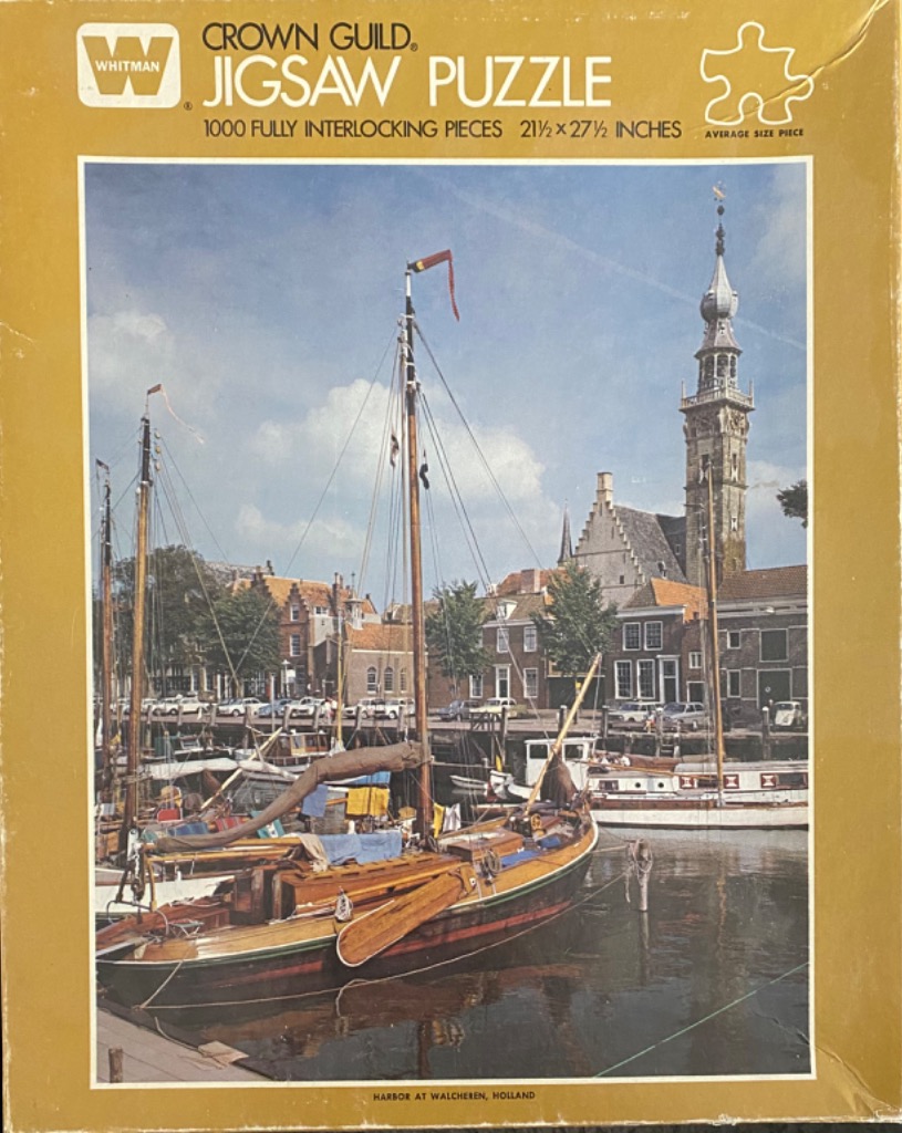 A peaceful harbor scene in Walcheren, Holland, featuring traditional wooden sailboats moored before historic buildings.