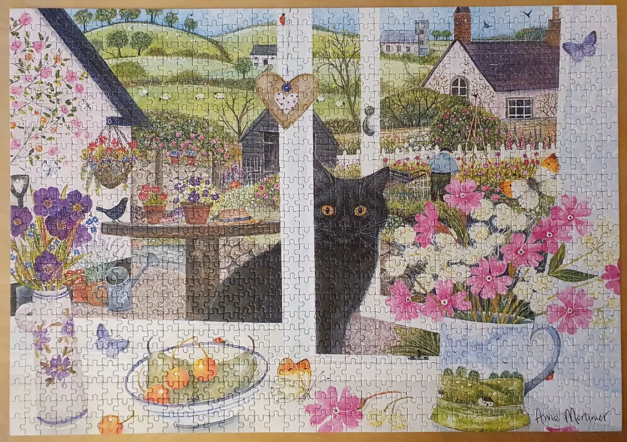 A black cat looks through a window frame onto a lush English garden scene.