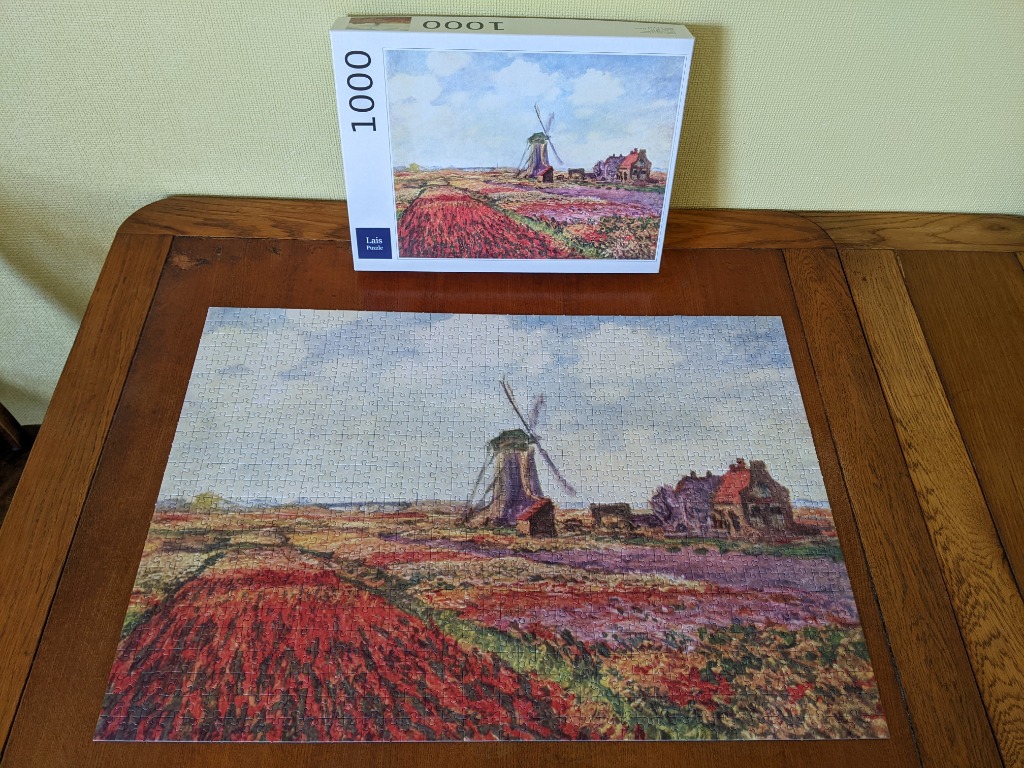 Impressionist-style painting of a Dutch landscape featuring a windmill and vibrant fields of flowers.
