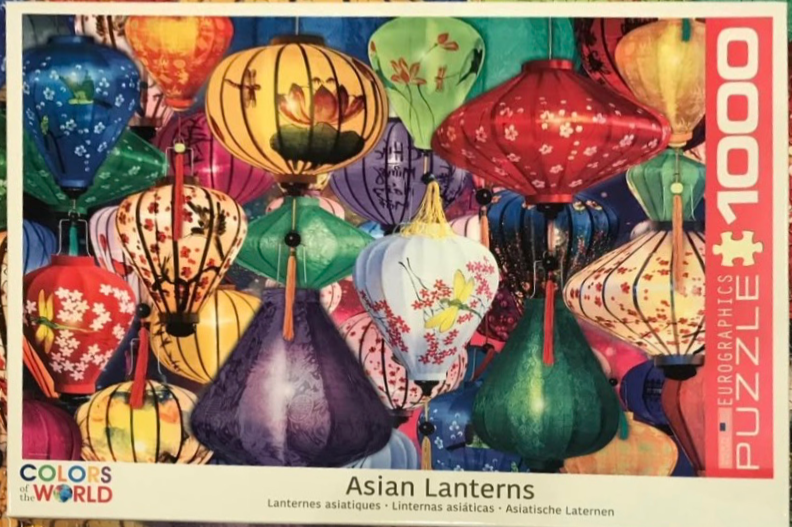 A dense cluster of colorful, patterned silk Asian lanterns in various shapes and sizes.