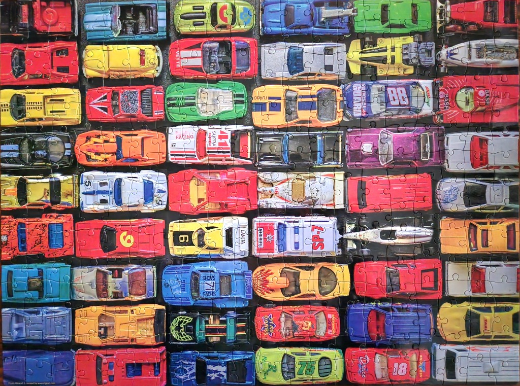 A top-down collection of many different toy cars arranged in a grid pattern.