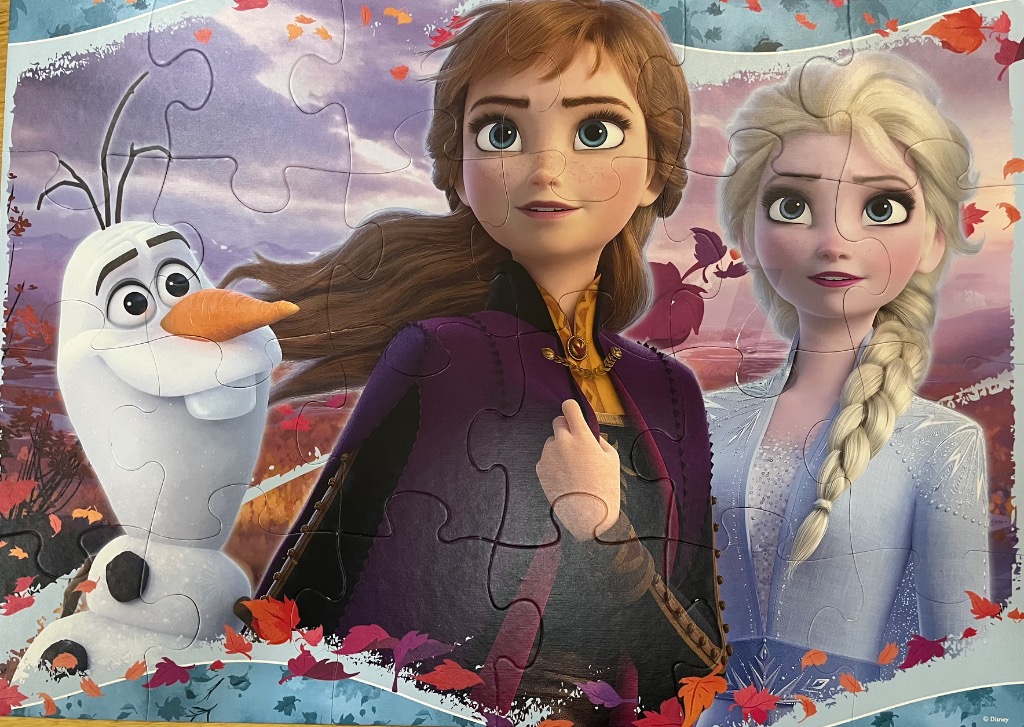 Anna, Elsa, and Olaf from Frozen 2 against a background of autumn leaves and a hazy landscape.