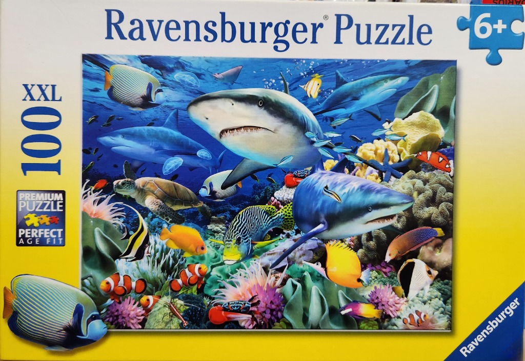 Vibrant underwater scene featuring two sharks, a sea turtle, and numerous tropical fish swimming among coral reefs.