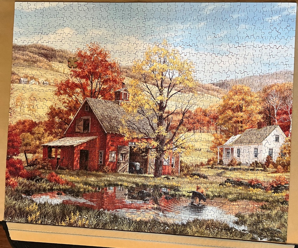 A peaceful autumn landscape featuring a red barn, a white farmhouse, and a pond with two dogs in the foreground.