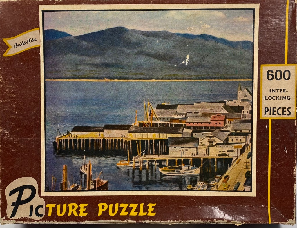 A vintage painting of a coastal harbor with docks, fishing boats, and mountains in the background.