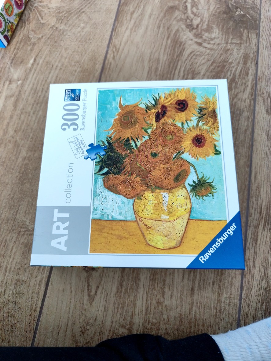A print of Vincent van Gogh's Sunflowers in a yellow vase against a turquoise background.