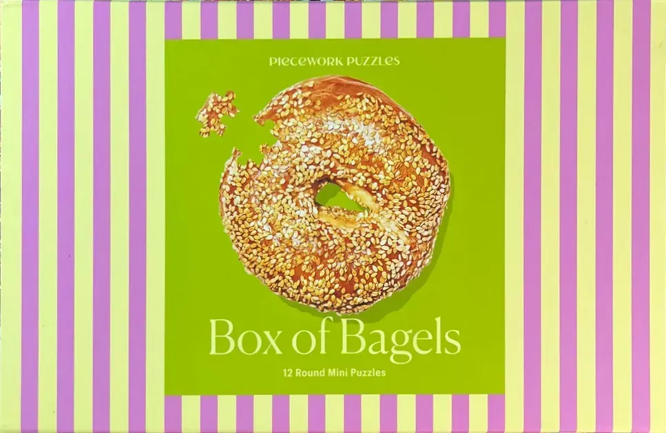 A sesame bagel with a missing piece on a bright lime green background with purple and yellow stripes.