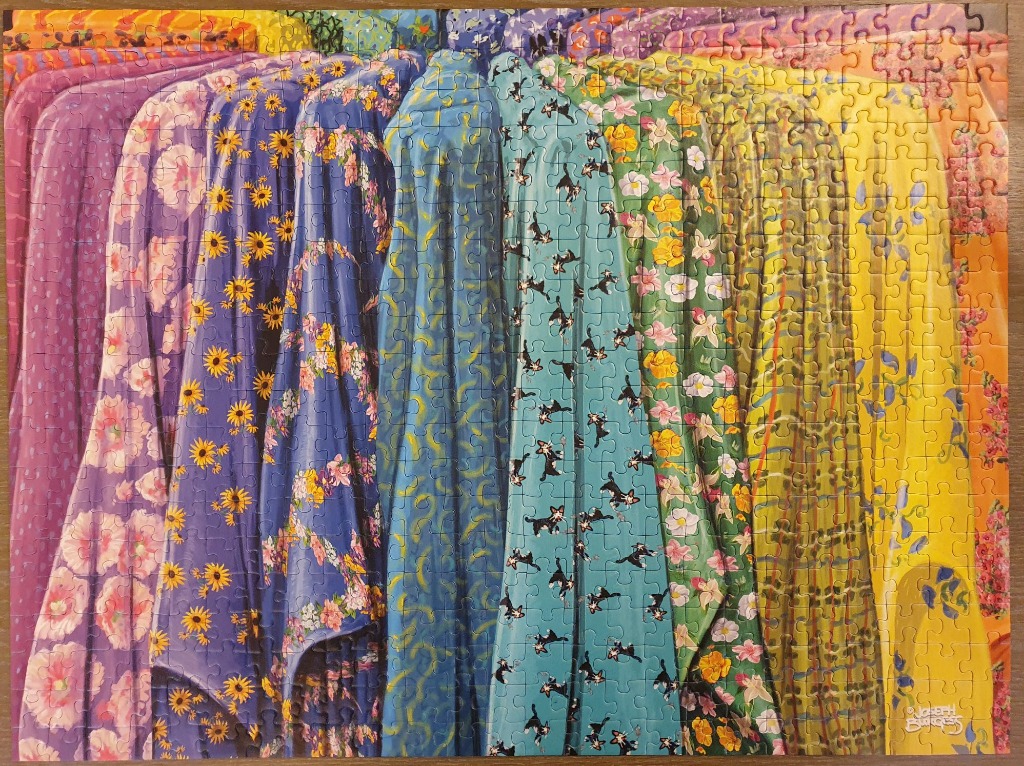 Rows of vibrant, patterned fabrics hanging in a rainbow spectrum gradient.