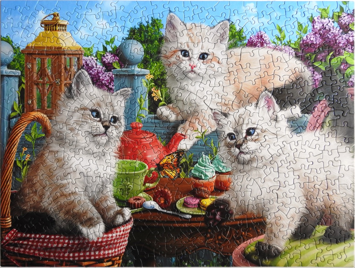 Three fluffy kittens gathered around a garden tea party setting with a wicker basket and blooming lilacs.