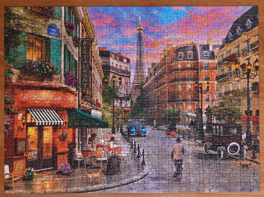 A nostalgic street scene in Paris at sunset with a view of the Eiffel Tower, cafes, and vintage vehicles.