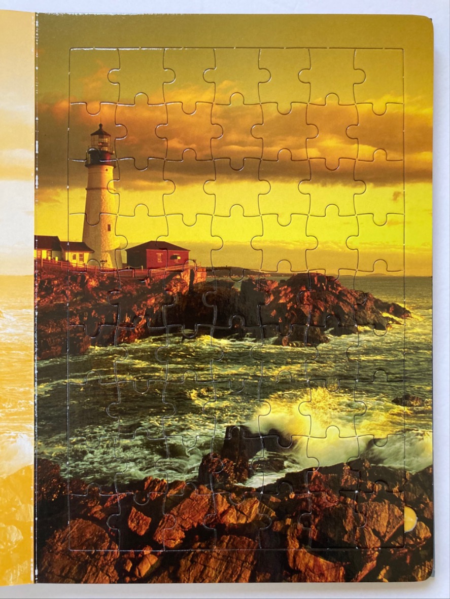 A lighthouse standing on a rocky coast at sunset with crashing waves.