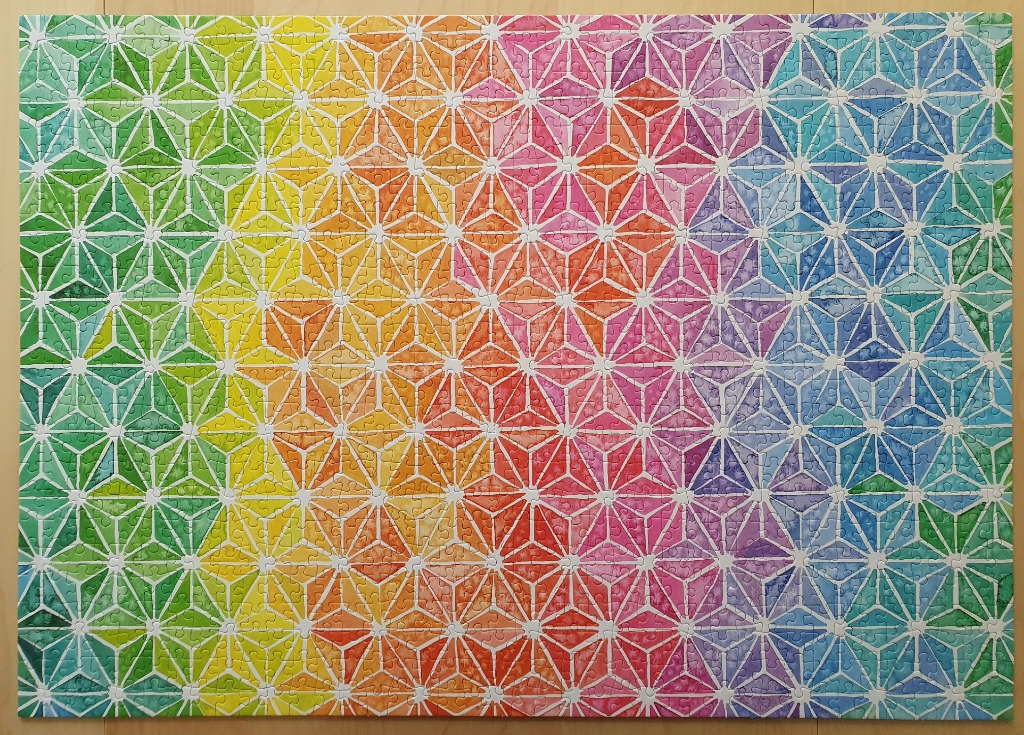 A vibrant geometric pattern of triangles creating six-pointed stars in a spectrum of watercolor rainbow colors.