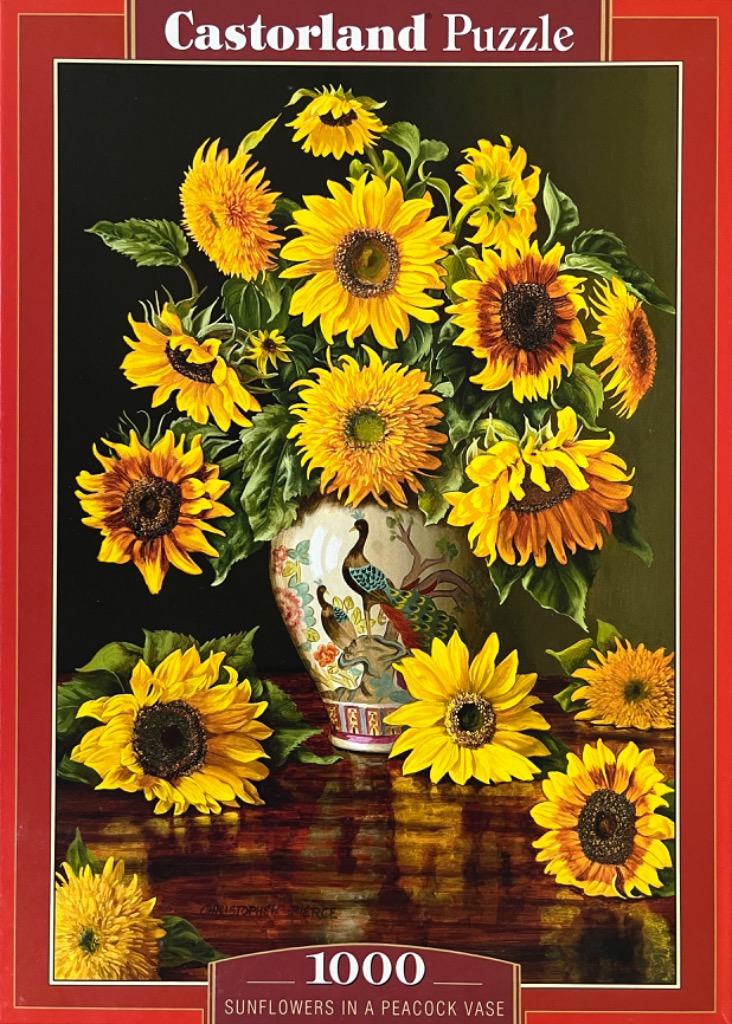 A lush bouquet of bright yellow sunflowers in a decorative porcelain vase with a peacock motif on a dark wooden table.