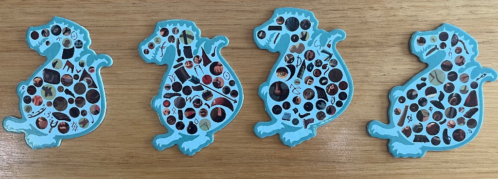 Four blue dinosaur-shaped silhouettes filled with various circular image fragments on a wooden surface.