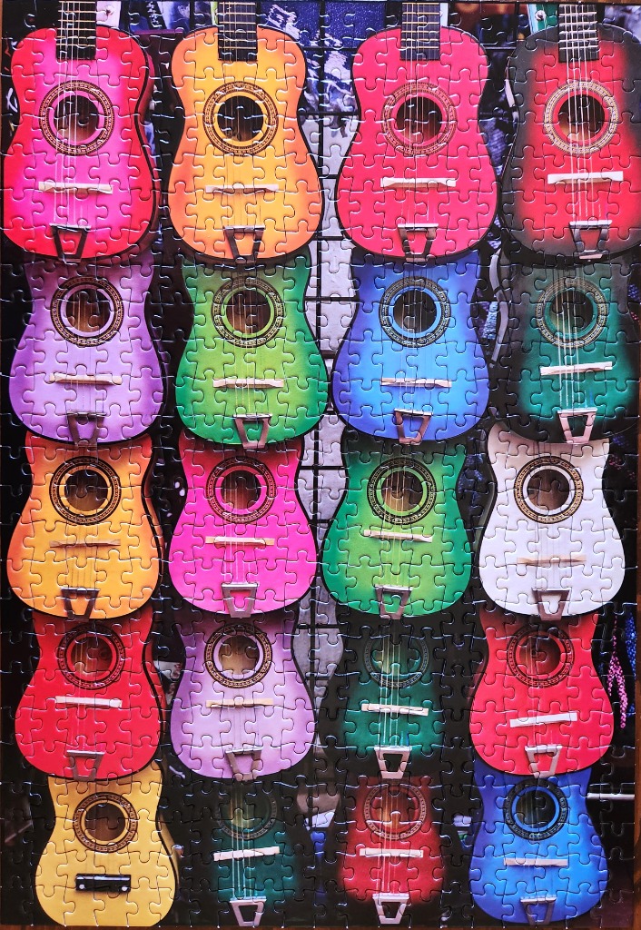 A grid of colorful acoustic guitars hanging against a black wire display rack.