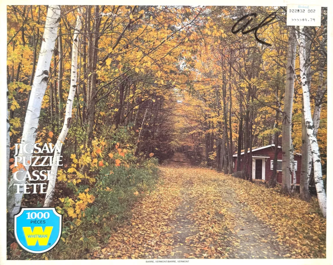 A wooded path in autumn lined with white birch trees and a small red cabin.