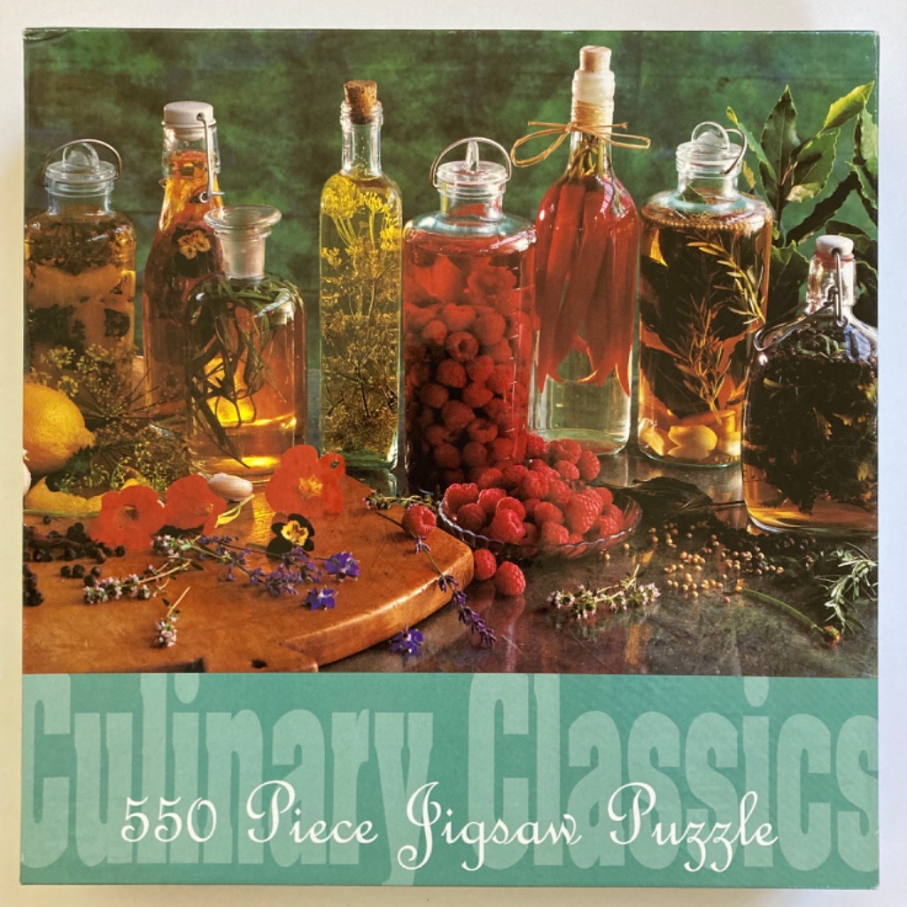 A still life photograph featuring various glass bottles filled with infused oils, herbs, berries, and chili peppers.