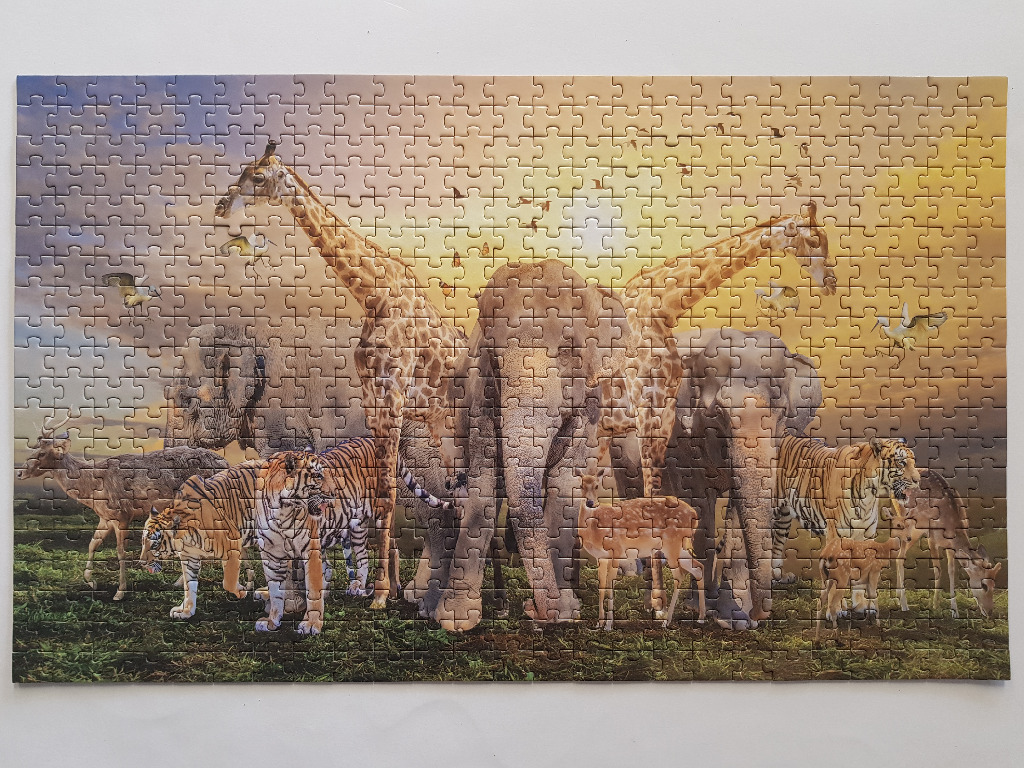 A gathering of various wild animals including elephants, giraffes, tigers, and deer at sunset.