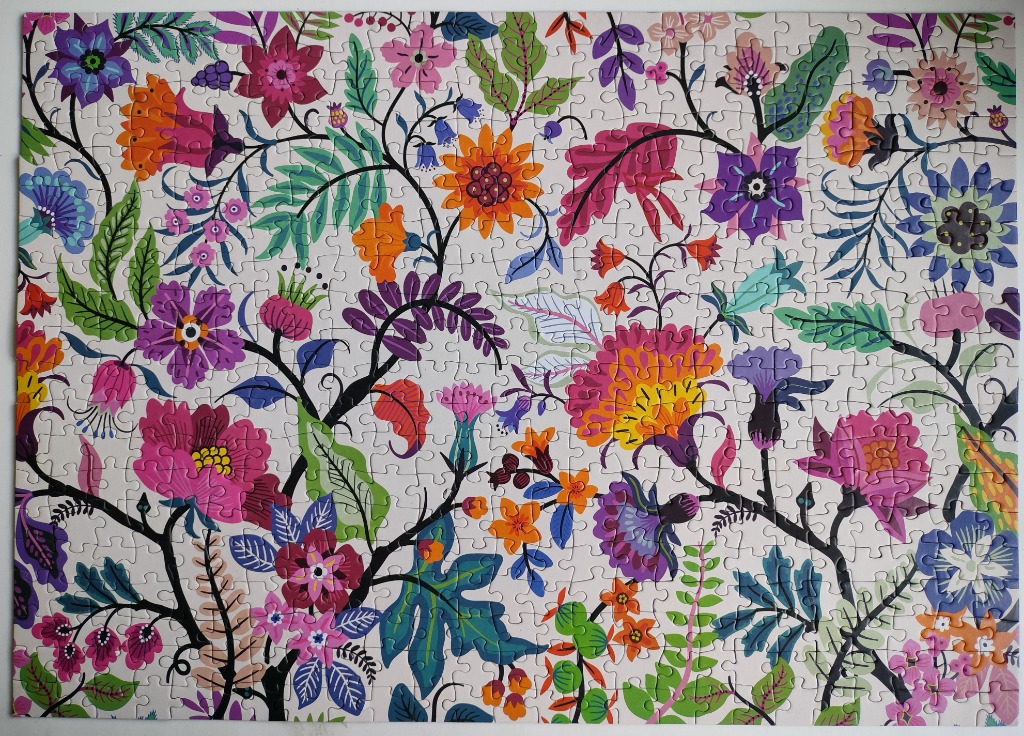A vibrant, hand-drawn floral pattern with diverse blooms, scrolling black vines, and green leaves on a cream background.