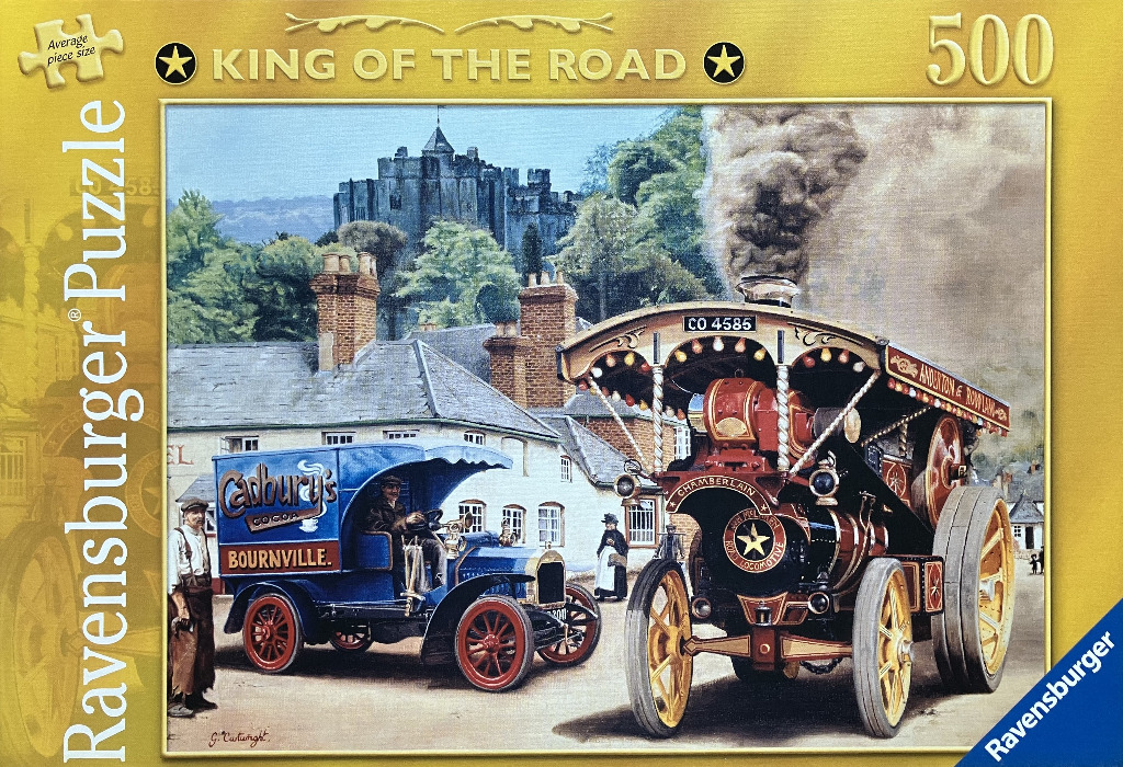 A vintage steam traction engine and a Cadbury blue delivery van parked in front of a stone village and castle.