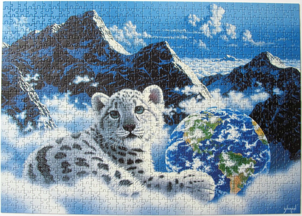 A snow leopard cub resting against a globe of the Earth in front of snowy mountain peaks.