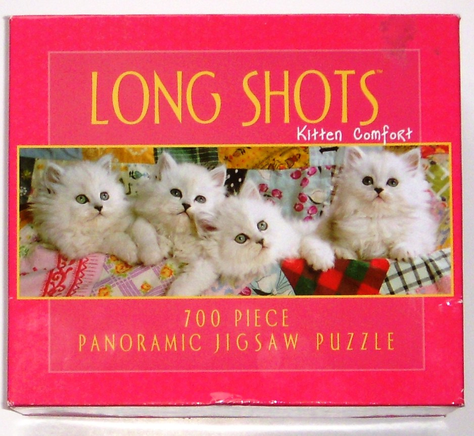 Four fluffy white kittens resting together on a colorful patchwork quilt.