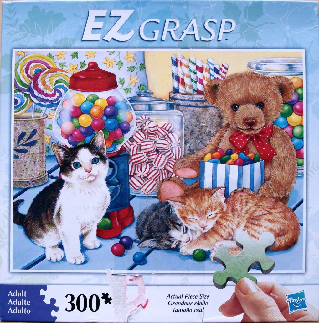 Two kittens and a teddy bear in a candy shop setting