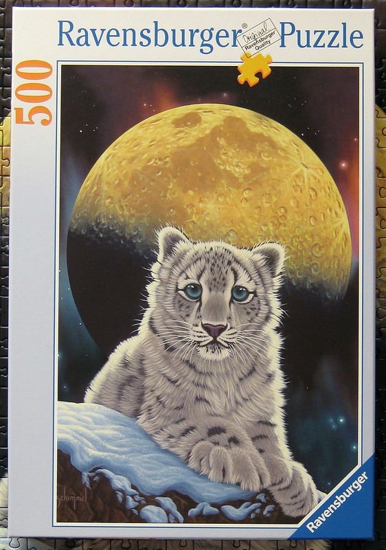A snow leopard cub resting on a snowy ledge against a backdrop of a large, glowing full moon in space.