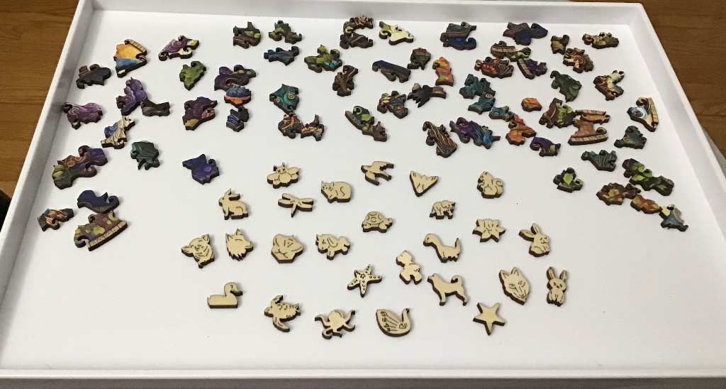 A collection of whimsical animal-shaped wooden pieces and decorative segments on a white tray.
