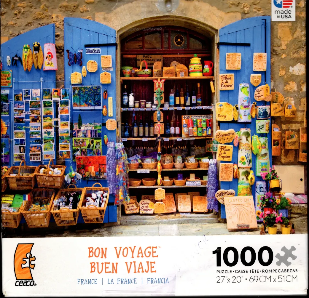 A charming French shop front featuring blue wooden doors decorated with souvenirs, postcards, and artisanal goods.