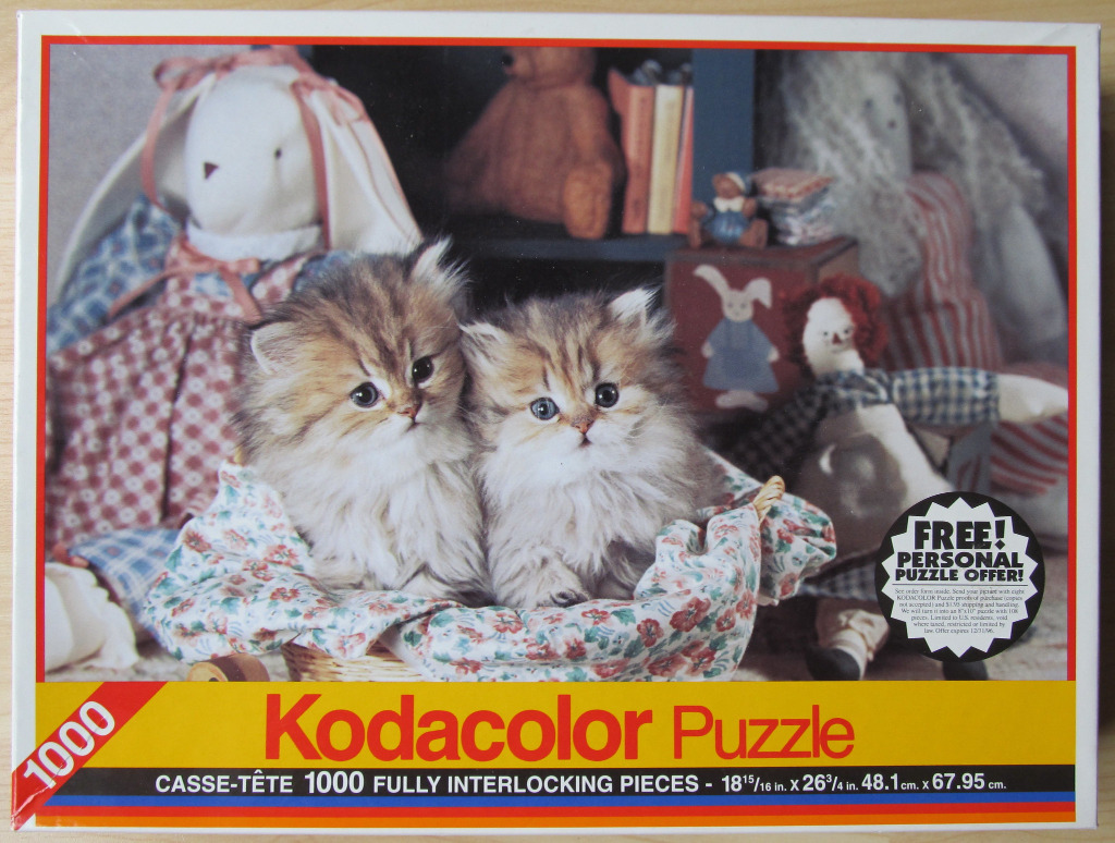 Two fluffy kittens sitting in a wicker basket surrounded by antique dolls.