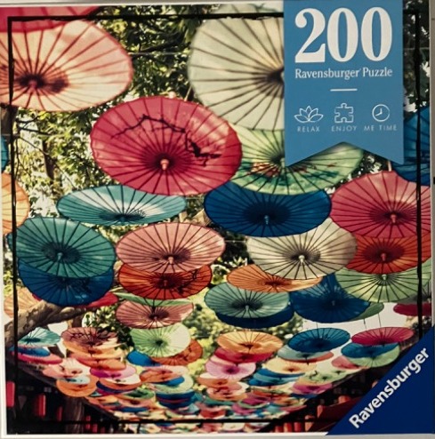 A canopy of colorful Japanese paper umbrellas suspended overhead in a lush garden setting.