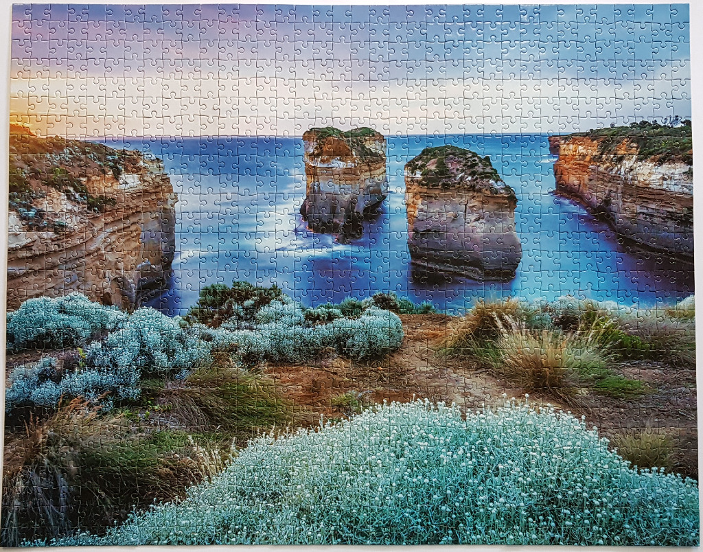 Coastal view of limestone sea stacks at dusk with silvery coastal vegetation in the foreground.