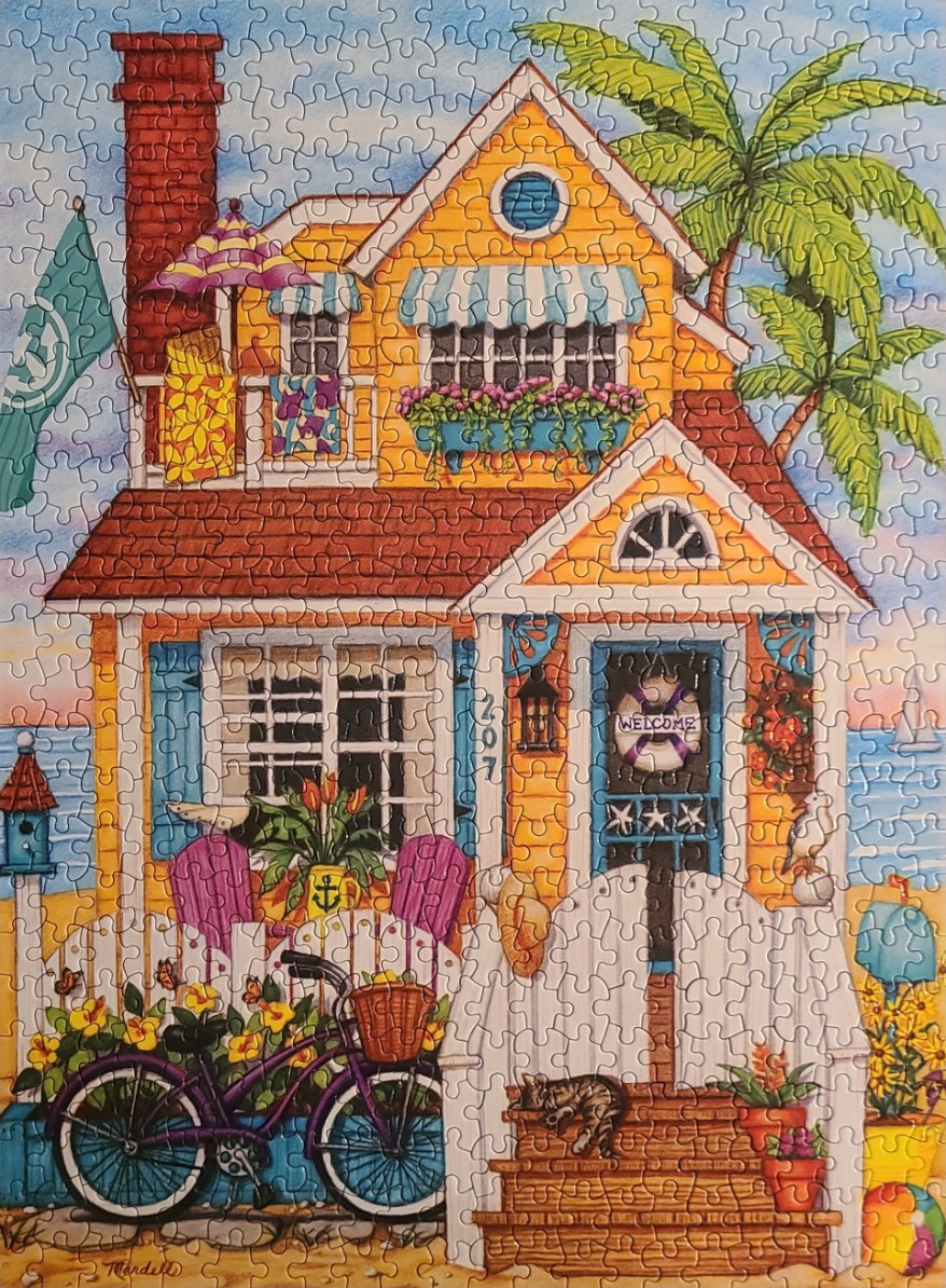 A sunny yellow beach house with a purple bicycle, white picket fence, and ocean view.