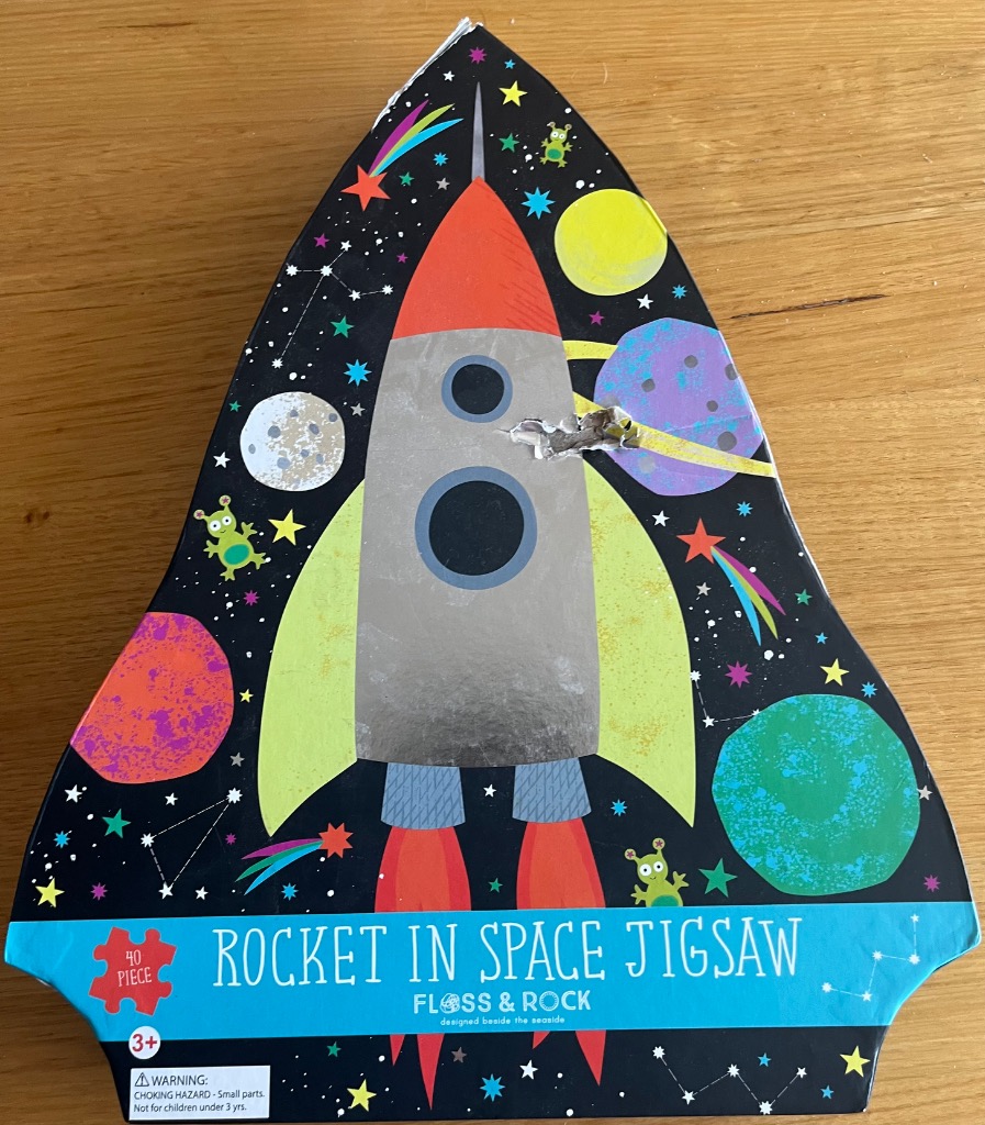 Cartoon rocket ship surrounded by planets and aliens against a starry black sky