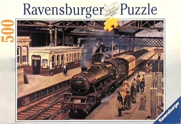 A vintage steam locomotive at a railway station with passengers waiting on the platform.