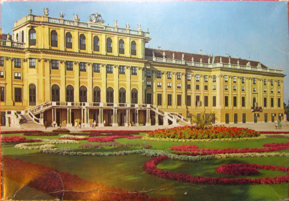A photograph of the yellow Schönbrunn Palace in Vienna with formal garden beds in the foreground.