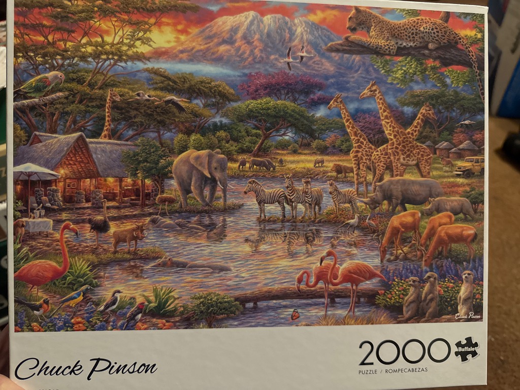 An illustration of an African savanna teeming with diverse wildlife near a watering hole at sunset.