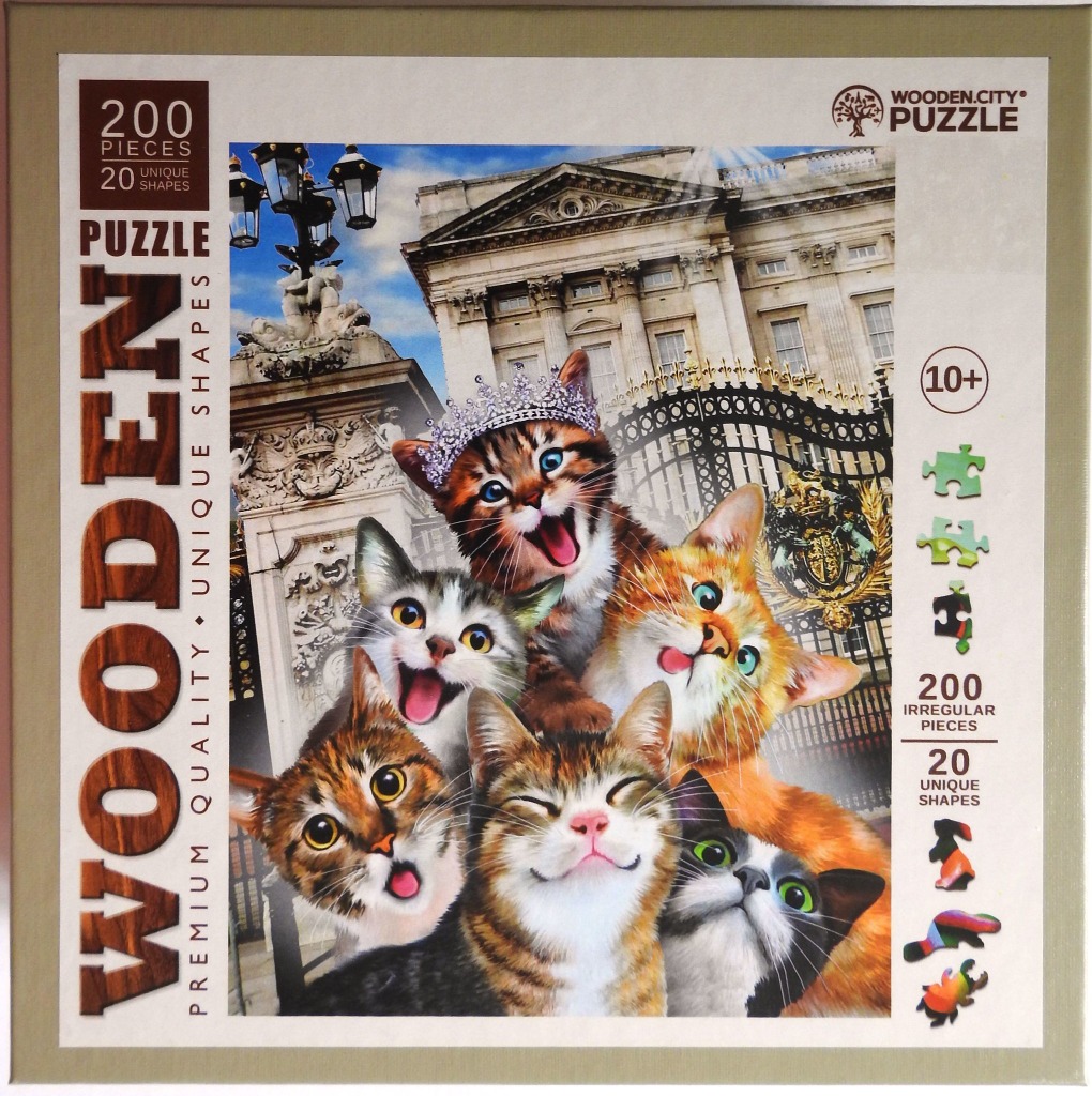 Six kittens with expressive faces posed in front of Buckingham Palace gates.