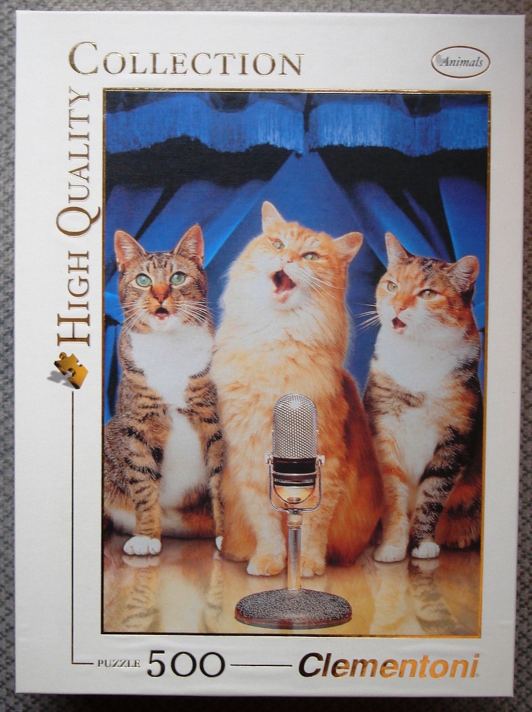 Three cats singing into a vintage microphone against a blue curtain backdrop.
