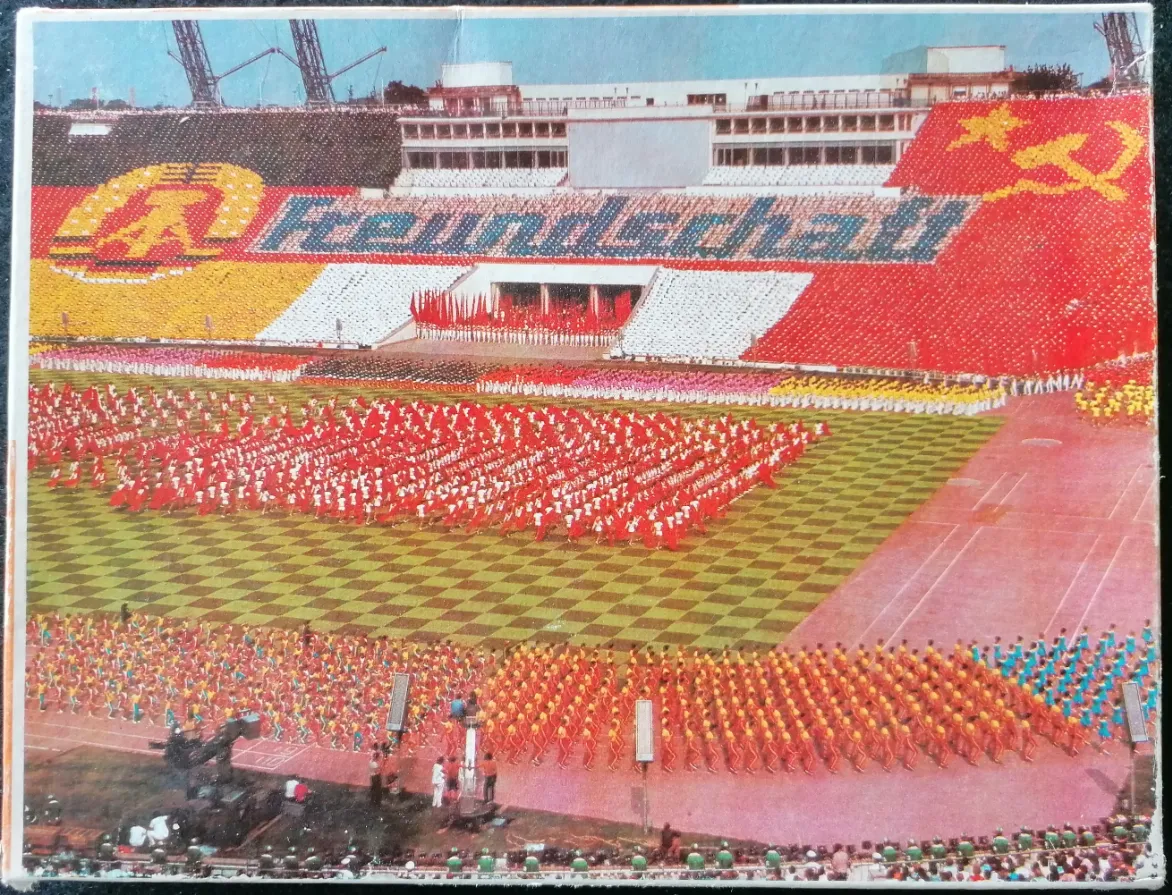 Aerial view of a mass stadium display with synchronized performers forming the German flag and the word Freundschaft.